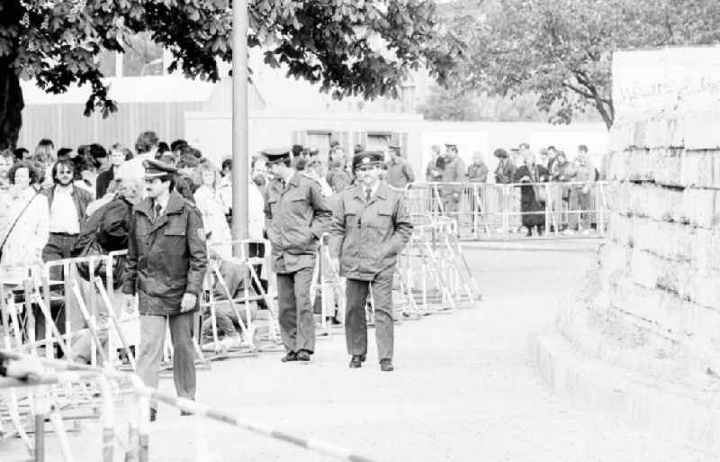 Berliner Polizeibeamte (zwei dovon Volkspolizisten) hinter Absperrung vor dem Panzerwall am Tag vom Abriß / Mauerabbau der Panzermauer / Panzerwall am Brandenburger Tor. Menschen / Passanten am Grenzübergang im Hintergrund.