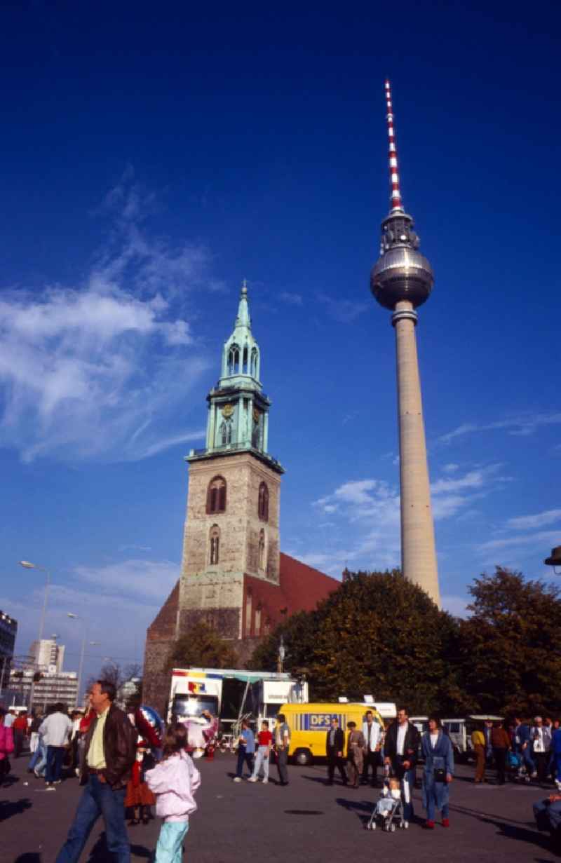 View of the TV tower with the Protestant Marienkirche in Berlin - Mitte. The Berlin TV Tower is the tallest building in Germany. As a politically simplistic ahmtes symbol of the GDR, the distinctive and influential city building has undergone a transition to the citywide icon in reunited Berlin