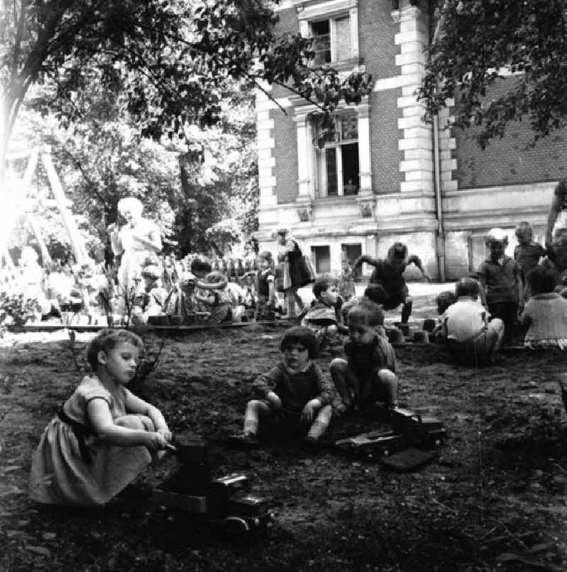 Kinder / Kleinkinder spielen im Sandkasten / Buddelkasten auf Kindergarten-Spielplatz.