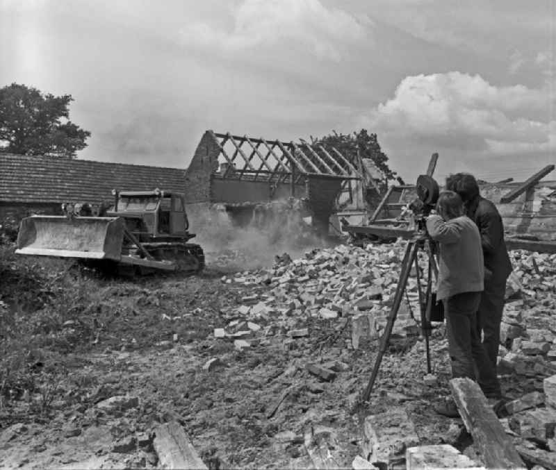 Scene from the film and television production 'Struga - Pictures of a Landscape' in a demolition area for a brown coal open-cast mine in the Lausitz region of Saxony in the area of the former GDR, German Democratic Republic. A tracked excavator is tearing down an old abandoned farmstead