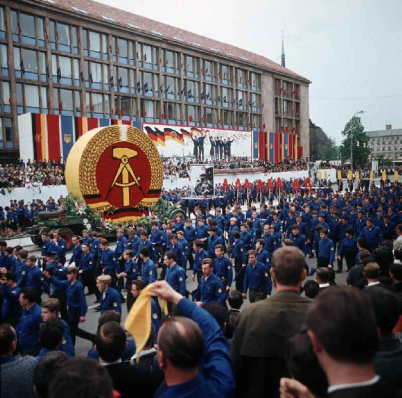 Eine Demonstration der FDJ marschiert während des FDJ-Pfingsttreffens in Karl-Marx-Stadt, heute Chemnitz, auf der Straße der Nationen. Auf einem Wagen wird ein großes Staatswappen der DDR vorbeigefahren. Bei den alle fünf Jahre stattfindenden Pfingsttreffen kamen Zehntausende delegierte Mitglieder der FDJ aus der ganzen DDR zusammen.