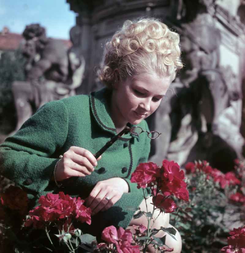 Young woman presents current womens fashion collection with historical binoculars in her hand in Dresden, Saxony in the area of the former GDR, German Democratic Republic