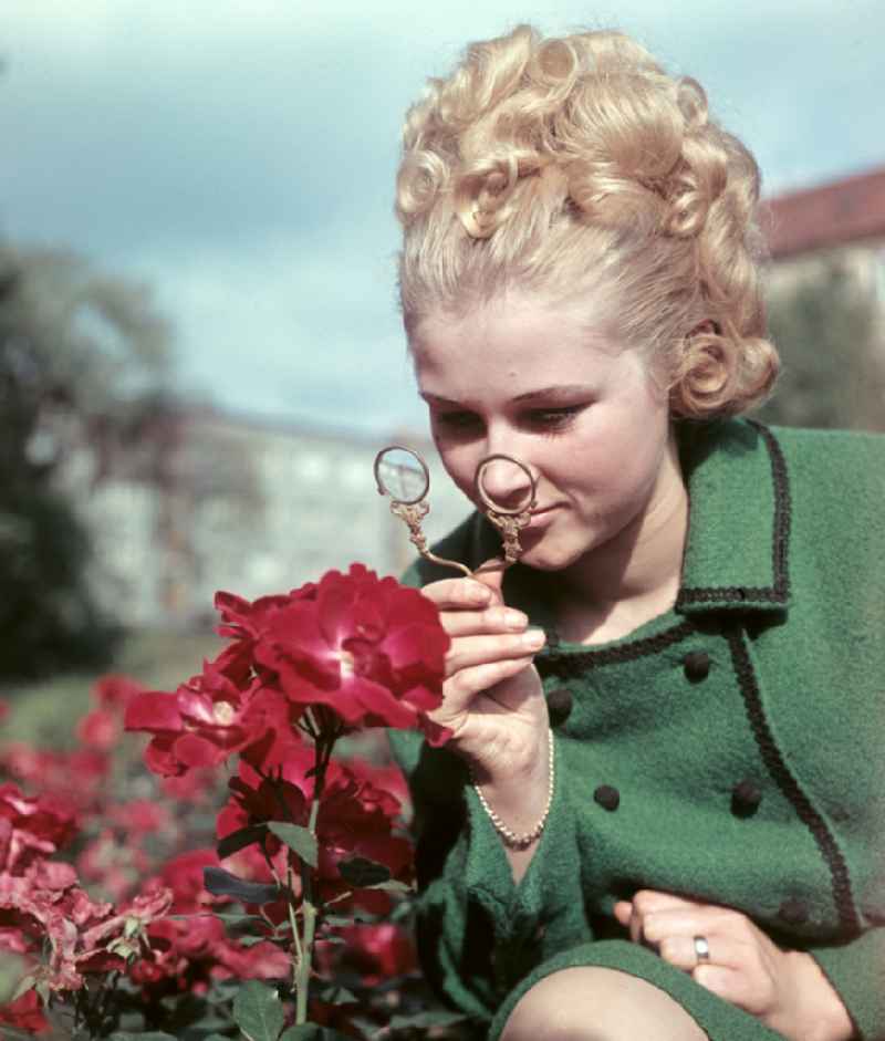 Young woman presents current womens fashion collection with historical binoculars in her hand in Dresden, Saxony in the area of the former GDR, German Democratic Republic