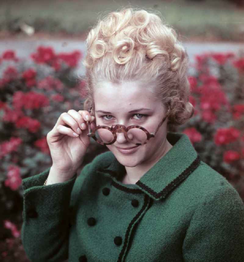 Young woman presents current womens fashion collection with historical binoculars in her hand in Dresden, Saxony in the area of the former GDR, German Democratic Republic