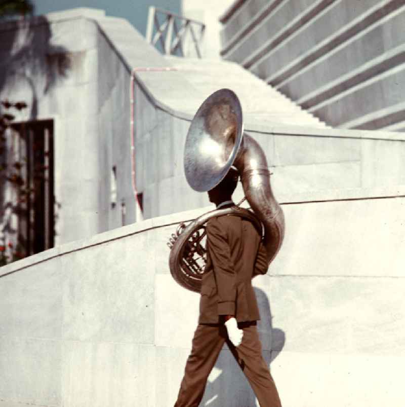 Tubaspieler auf dem Weg zu seiner Musikkapelle anläßlich der Kranzniederlegung des Staats- und Parteivorsitzenden der DDR, Erich Honecker, auf dem Plaza de la Revolución (Platz der Revolution) mit dem José-Martí-Denkmal in Havanna. Honecker stattete vom 2