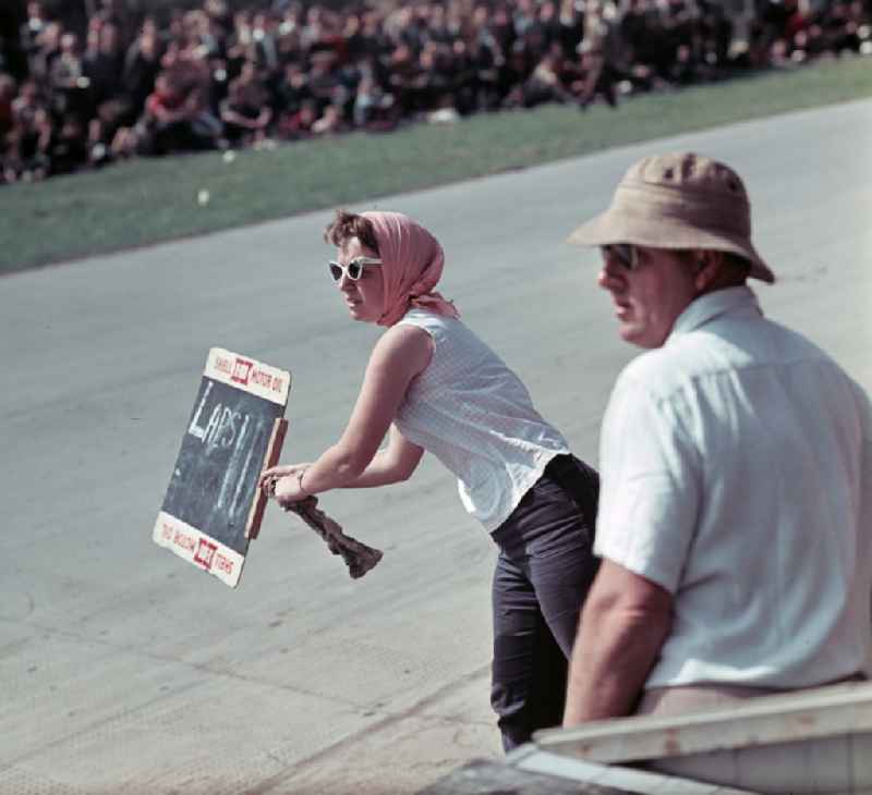 A woman holds a board with the number of laps on the race track during the race at the motorcycle race on the Sachsenring in Hohenstein-Ernstthal, Saxony in the territory of the former GDR, German Democratic Republic