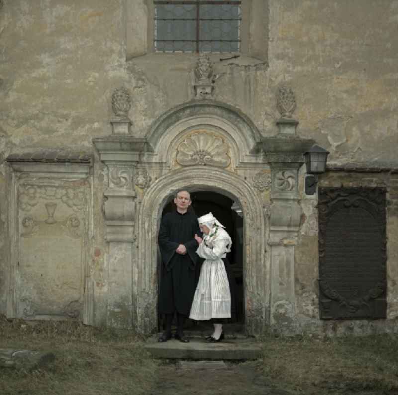 Scene from the film and television production 'Continent Hope' with the actress Majka Kowarjec and the actor Alfred Luebke at the entrance of a church in Kreba-Neudorf, Saxony in the area of the former GDR, German Democratic Republic