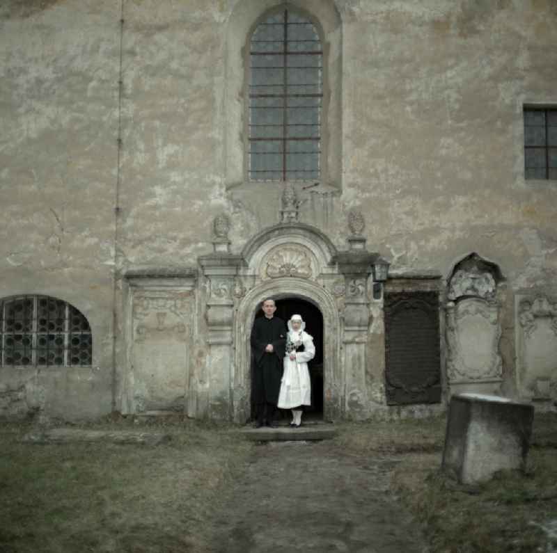 Scene from the film and television production 'Continent Hope' with the actress Majka Kowarjec and the actor Alfred Luebke at the entrance of a church in Kreba-Neudorf, Saxony in the area of the former GDR, German Democratic Republic