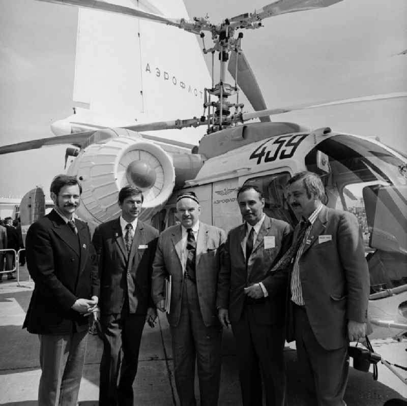 Nikolai Iljitsch Kamow (Mitte), ehemaliger Chefkonstrukteur des sowjetischen / russischen Hubschrauberherstellers Kamow / Kamov auf der Paris Air Show. Im Gespräch mit Vertretern der Presse, Ausstellern und Piloten. Im Hintergrund ein Zivilhubschrauber der Aeroflot vom Typ Kamow Ka-26.