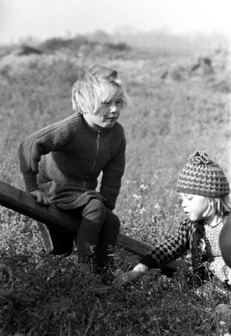 Während die Mütter bei der Ernte auf dem Land mithelfen müssen, spielen die Kinder in der Nähe auf dem Feld.