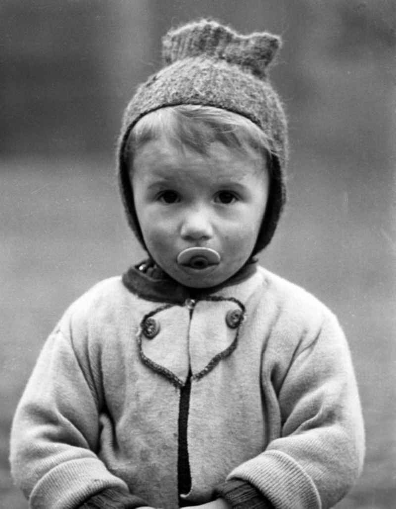 Mit großen Augen schaut dieser kleine Junge - den Nuckel halb im Mund - in die Kamera des Fotografe.