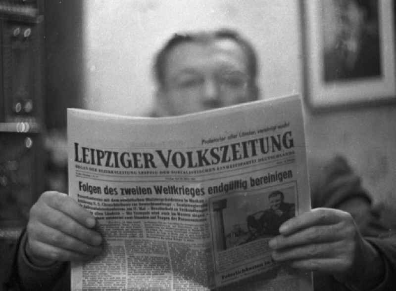 Ein Mann liest die Leipziger Volkszeitung, das 'Organ der Bezirksleitung Leipzig der Sozialistischen Einheitspartei Deutschlands'. Über dem Titel prangt 'Proletarier aller Länder, vereinigt Euch!' Die Schlagzeile des Tages lautete: 'Folgen des Zweiten Weltkrieges endgültig bereinigen'. [Schlechte Bildqualität vorlagebedingt.]