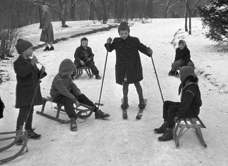 Von den anderen Kindern mit Schlitten bestaunt, fährt ein Mädchen auf ihren Skiern im Clara-Zetkin-Park den Hügel hinunter.