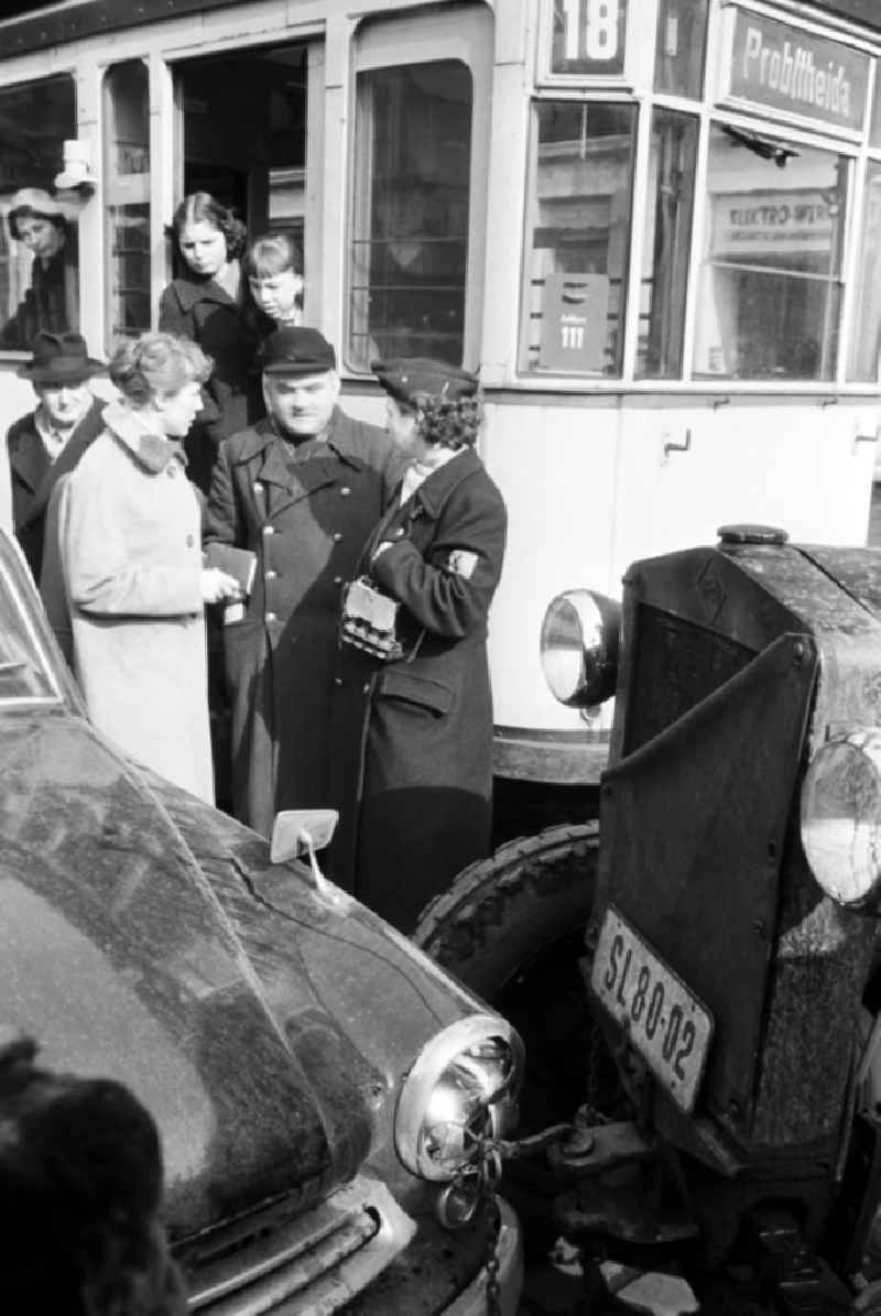 Ein Verkehrsunfall zwischen zwei Autos und einer Straßenbahn erregt schnell großes Aufsehen unter den Passanten in Leipzig - hier Schaffnerin und Autofahrer im Gespräch.