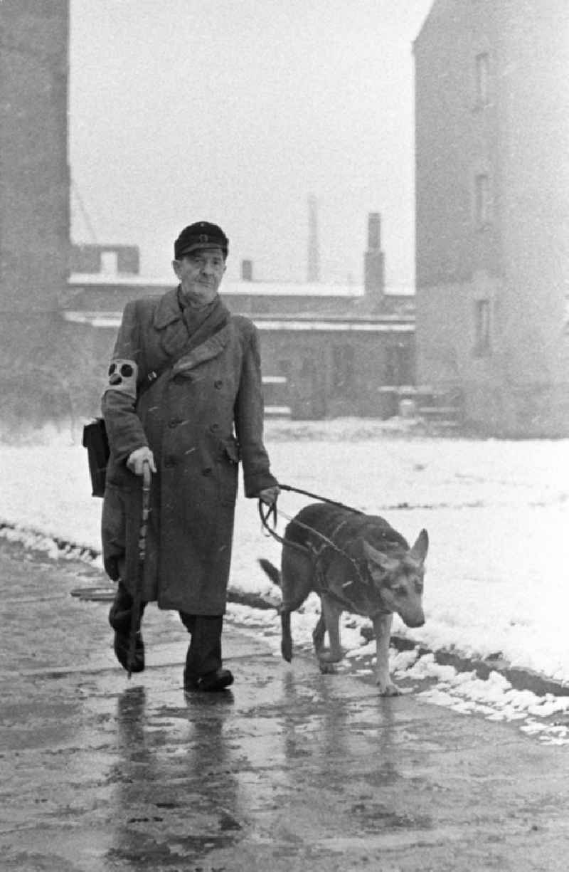 Ein blinder Mann mit Blindenzeichen und Stock geht mit seinem Hund in Leipzig spazieren.