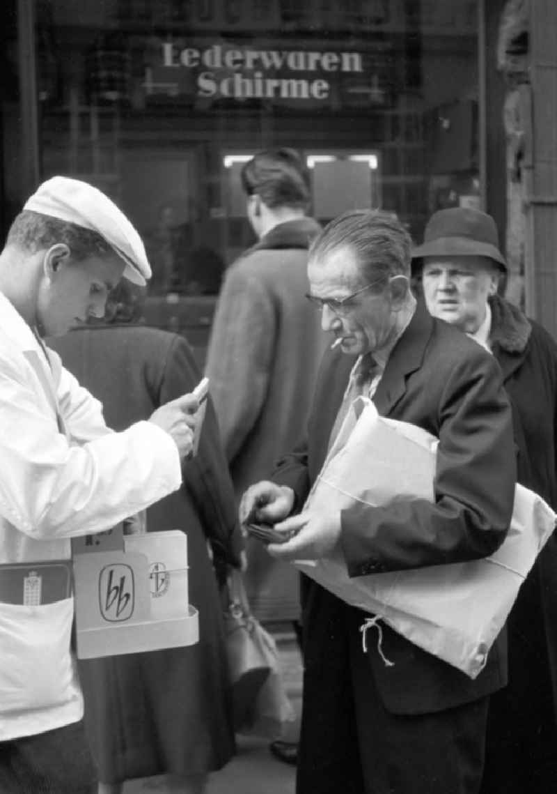 Ein alter Mann kauft bei einem Verkäufer mit Bauchladen in Leipzig ein Taschenbuch des Aufbau Verlages. Mit der Folge 'bb' für 'Billige Bücher' rief der größte belletristische Verlag der DDR 1958 seine erste Taschenbuchreihe ins Leben.