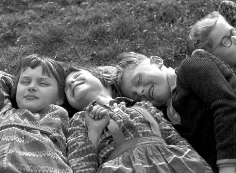 Vorschulkinder liegen auf einer Wiese im Clara-Zetkin-Park in Leipzig und ruhen sich aus.