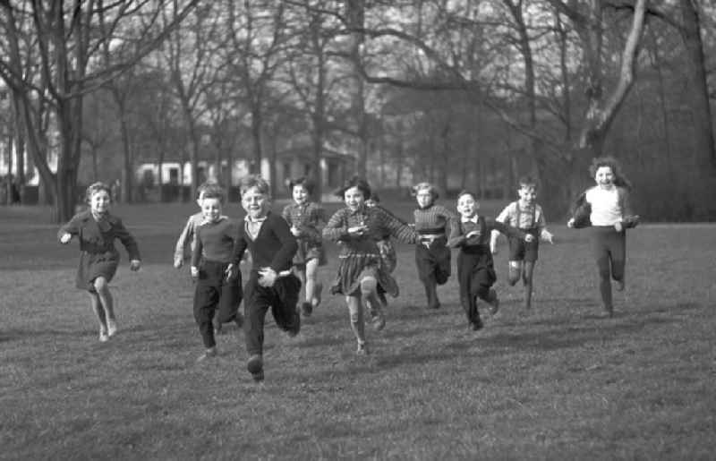 Eine Gruppe Vorschulkinder rennt lachend über eine Wiese im Clara-Zetkin-Park in Leipzig.