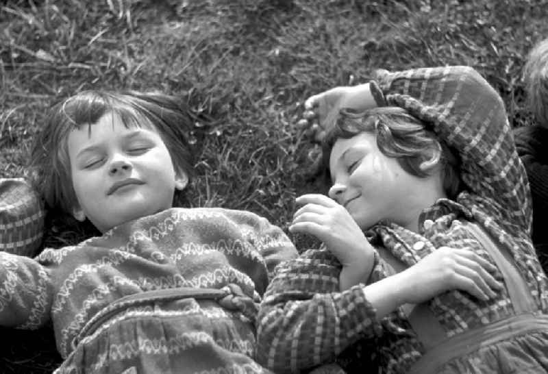 Vorschulkinder liegen auf einer Wiese im Clara-Zetkin-Park in Leipzig und ruhen sich aus.