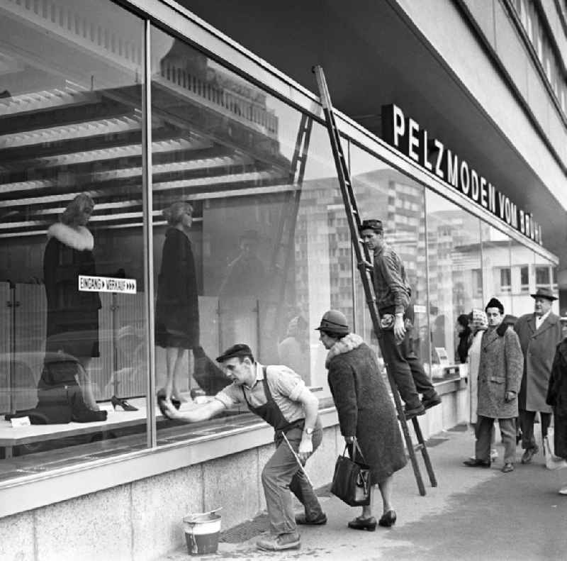 Während ältere Damen neugierig die Auslagen betrachten, reinigen zwei Fensterputzer die Schaufenster des Pelzmodengeschäftes vom Brühl in Leipzig. Das zehngeschossige Haus der Interpelz am Brühl (Hochhaus Brühlpelz) war 1966 eingeweiht worden. Dennoch errang der Brühl seinen Vorkriegsruf als Weltstraße der Pelze nicht zurück.