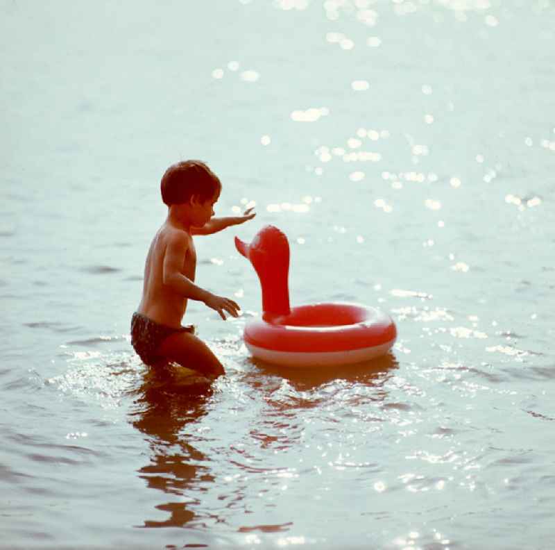 Ein kleiner Junge hat Spaß beim Baden mit seinem Schwimmreifen im Auensee in Leipzig.