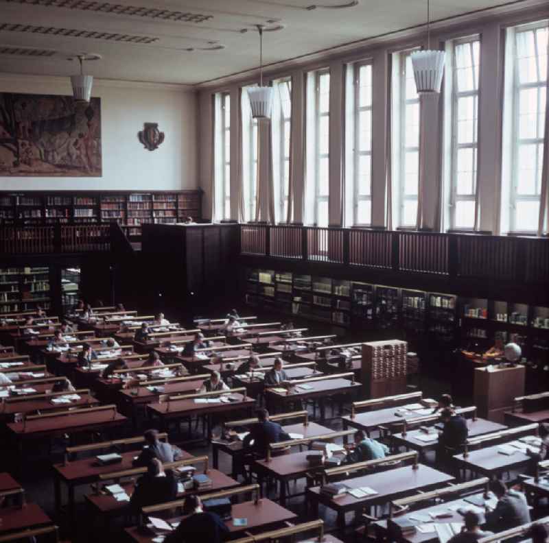 Besucher sitzen im großen Lesesaal der Deutschen Bücherei in Leipzig, im Hintergrund das Gemälde 'Arkadien' von Ludwig von Hofmann. Im Jahr 1912 als Gesamtarchiv des deutschsprachigen Schrifttums gegründet, behielt die Deutsche Bücherei in Leipzig auch in der DDR die Funktionen einer Nationalbibliothek bei. Nach der Wiedervereinigung erfolgte die Zusammenführung mit der Deutschen Bibliothek in Frankfurt/Main und dem Deutschen Musikarchiv zur DDB (Die Deutsche Bibliothek), 20