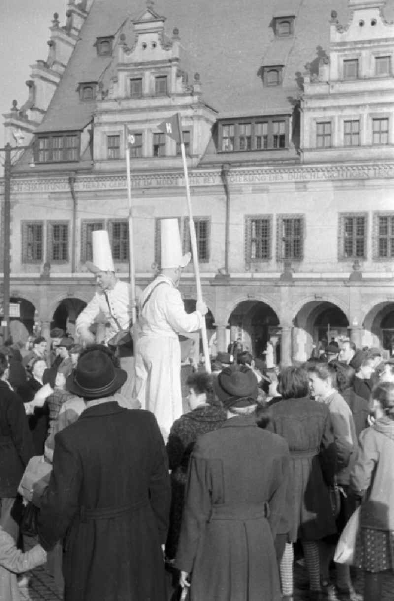 Zwei Männer als Vertreter der HO / Handelsorganisation machen eine Werbeaktion auf dem Markt in Leipzig. Um die Männer hat sich eine Menschenmenge versammelt. Im Hintergrund ist die Front-Fassade des Alten Rathaus zu sehen. Die HO war ein staatlich geführtes Einzelhandelsunternehmen, welches 1947 gegründet wurde.