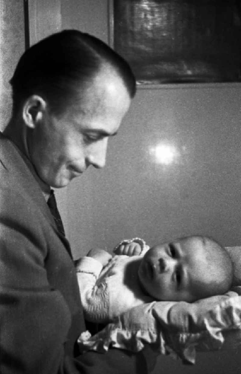 A father holds proudly his baby on the arm in Merseburg in the federal state Saxony-Anhalt in the area of the former GDR, German democratic republic