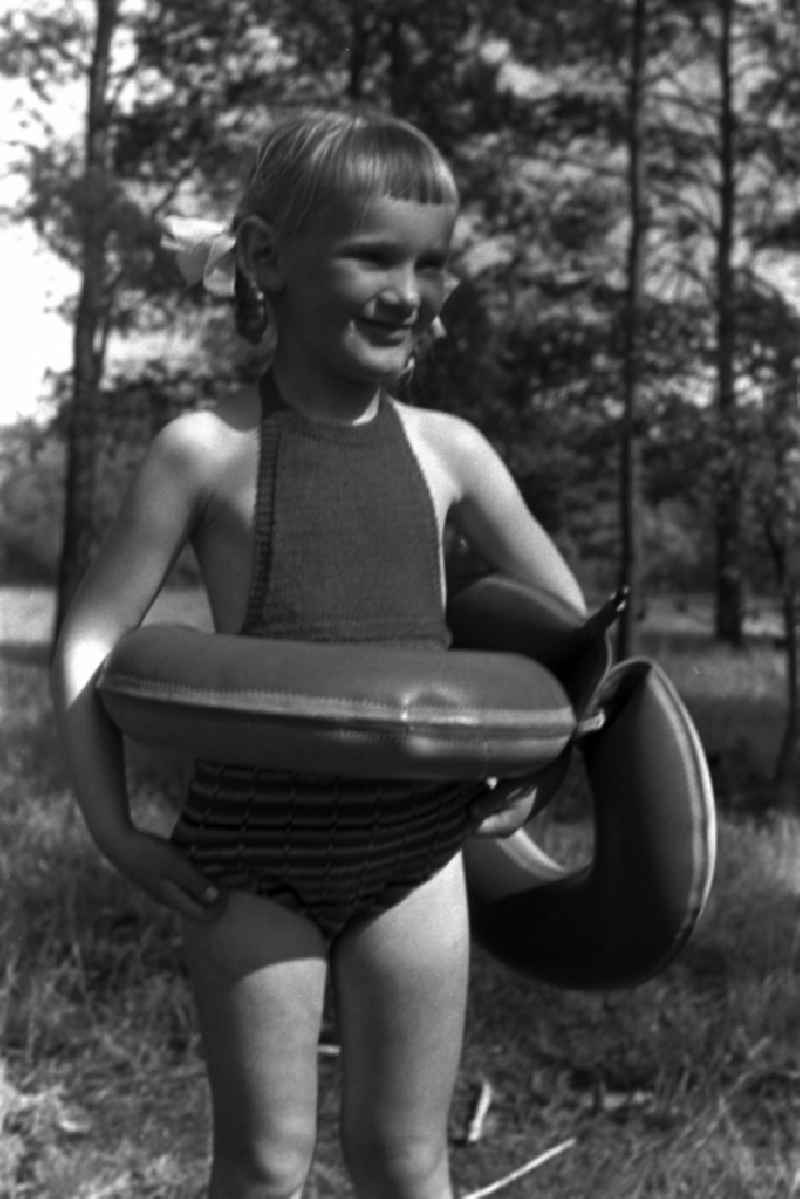 Girl with pigtails and swimming ring on a family holiday at the campsite On Rottstielfließ on Tornowsee in Brandenburg in Brandenburg