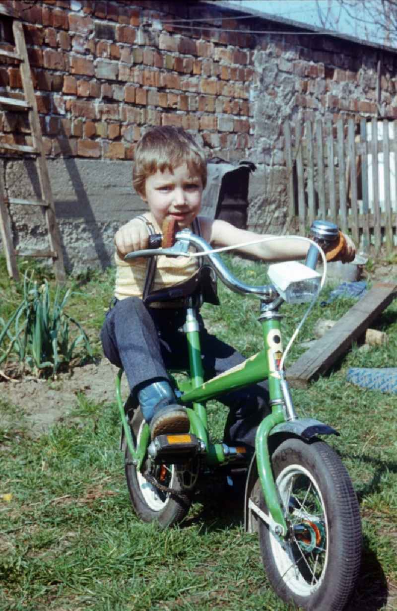 Boy on a green flash children's bicycle in Neustrelitz in the federal state Mecklenburg-West Pomerania in the area of the former GDR, German democratic republic