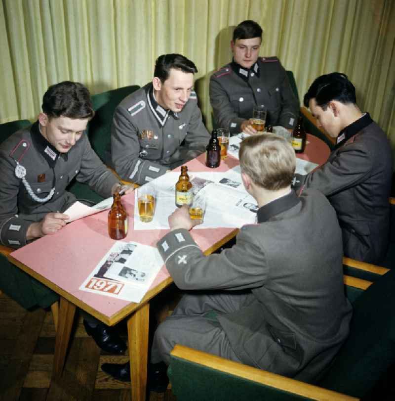 Soldiers - equipment and uniforms of the land forces of the NVA National Peoples Army in their free time reading the newspaper and drinking beer in the common room in a barracks accommodation in Oranienburg, Brandenburg in the territory of the former GDR, German Democratic Republic