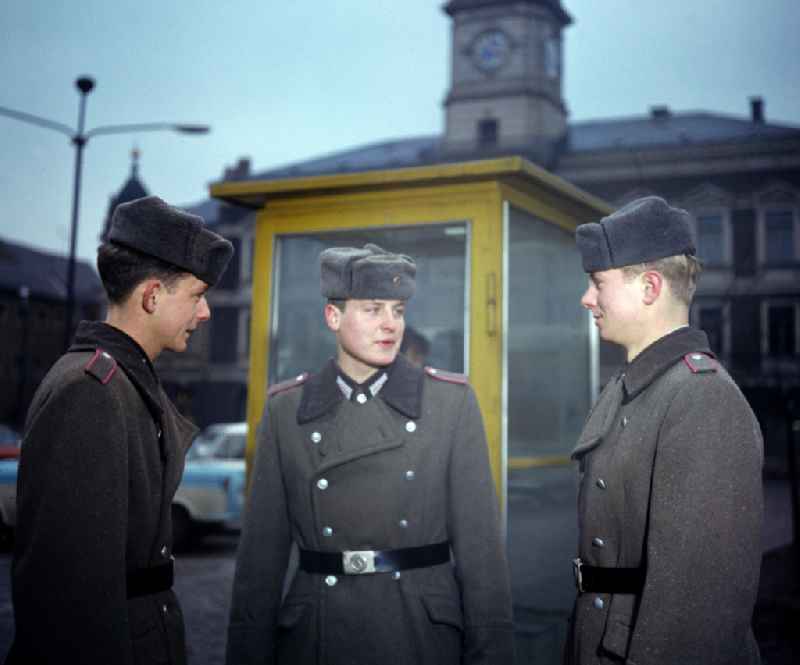 Soldiers - equipment and uniforms of the land forces of the NVA National Peoples Army in their free time at the exit in front of a telephone booth of the German Post Office after calling home in Oranienburg, Brandenburg in the territory of the former GDR, German Democratic Republic