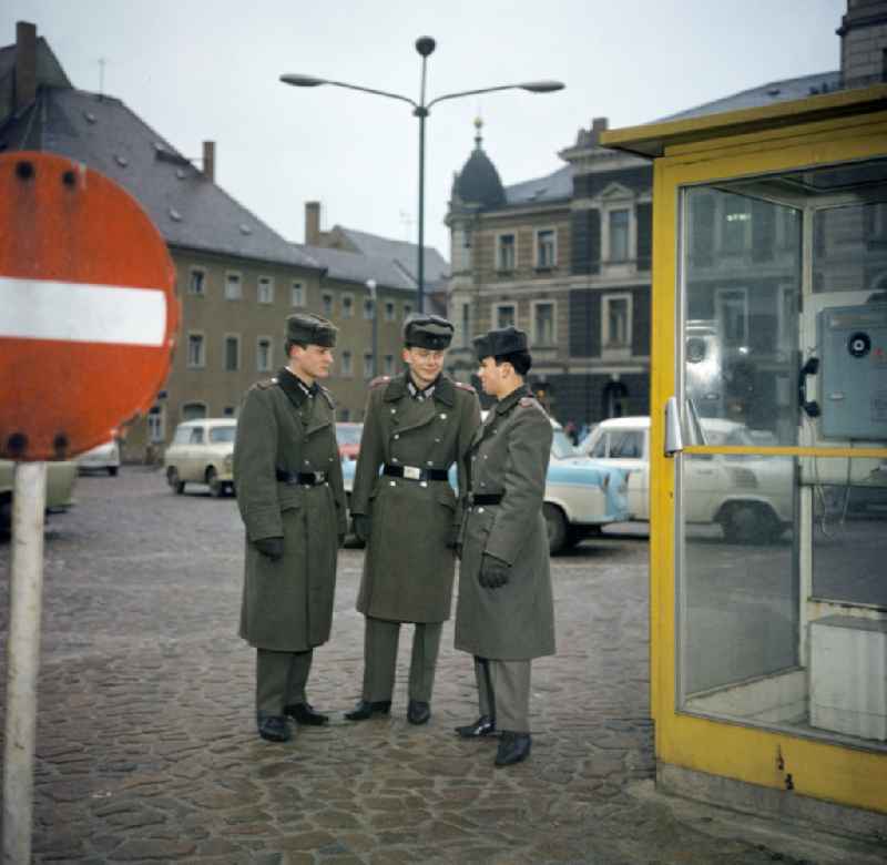 Soldiers - equipment and uniforms of the land forces of the NVA National Peoples Army in their free time at the exit in front of a telephone booth of the German Post Office after calling home in Oranienburg, Brandenburg in the territory of the former GDR, German Democratic Republic