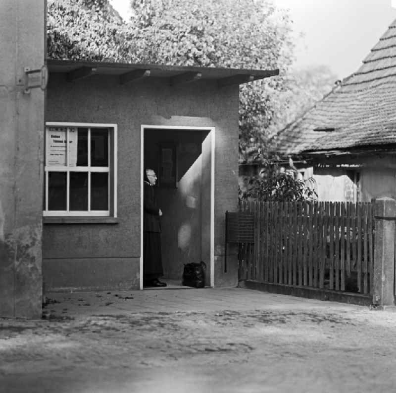 Elderly Sorbian farmers wife in everyday costume in the bus shelter on the main road in Raeckelwitz, Saxony in the area of the former GDR, German Democratic Republic