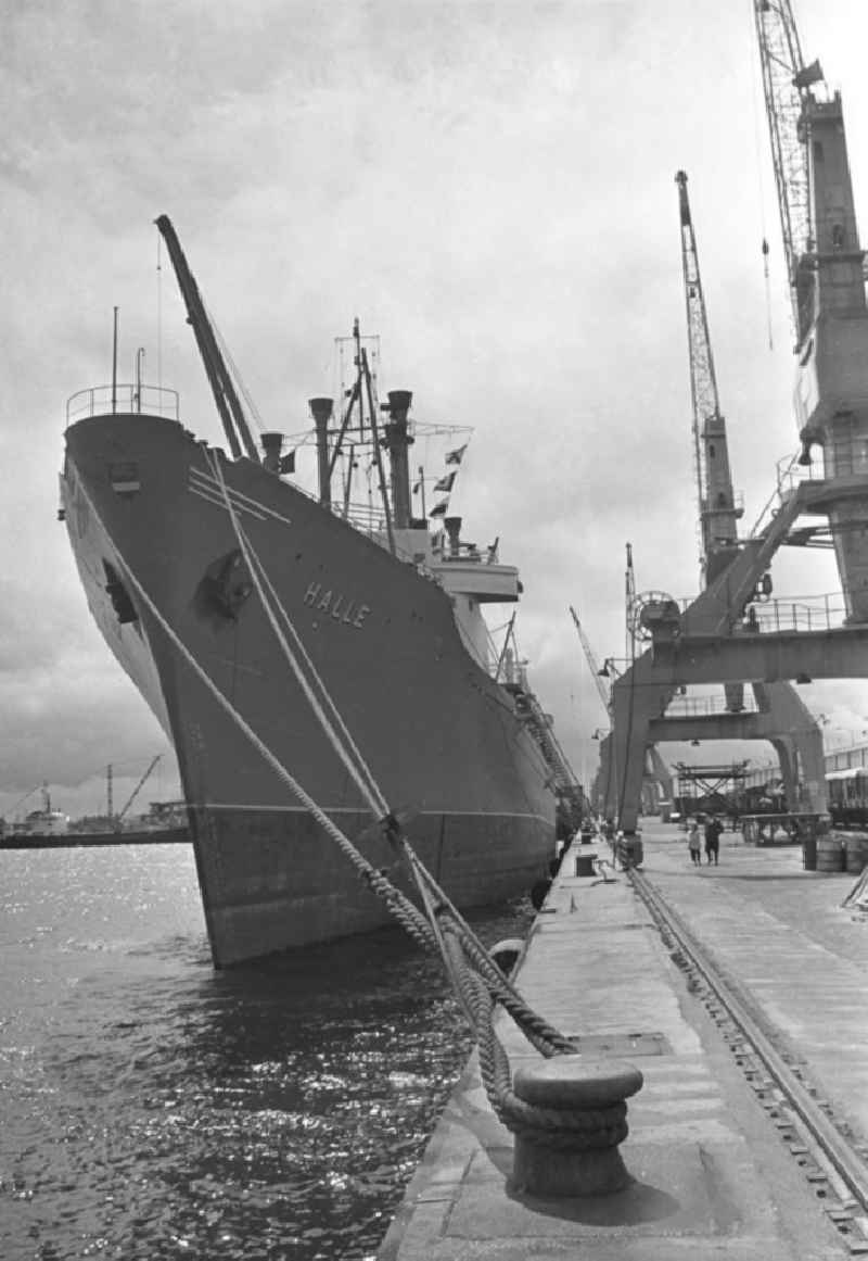 Das Schiff 'Halle' liegt vertäut im Seehafen in Rostock. Im Vordergrund das Schiffstau mit dem am Land / Hafengelände liegenden Poller. Der Hochseehafen wurde Anfang Mai 196