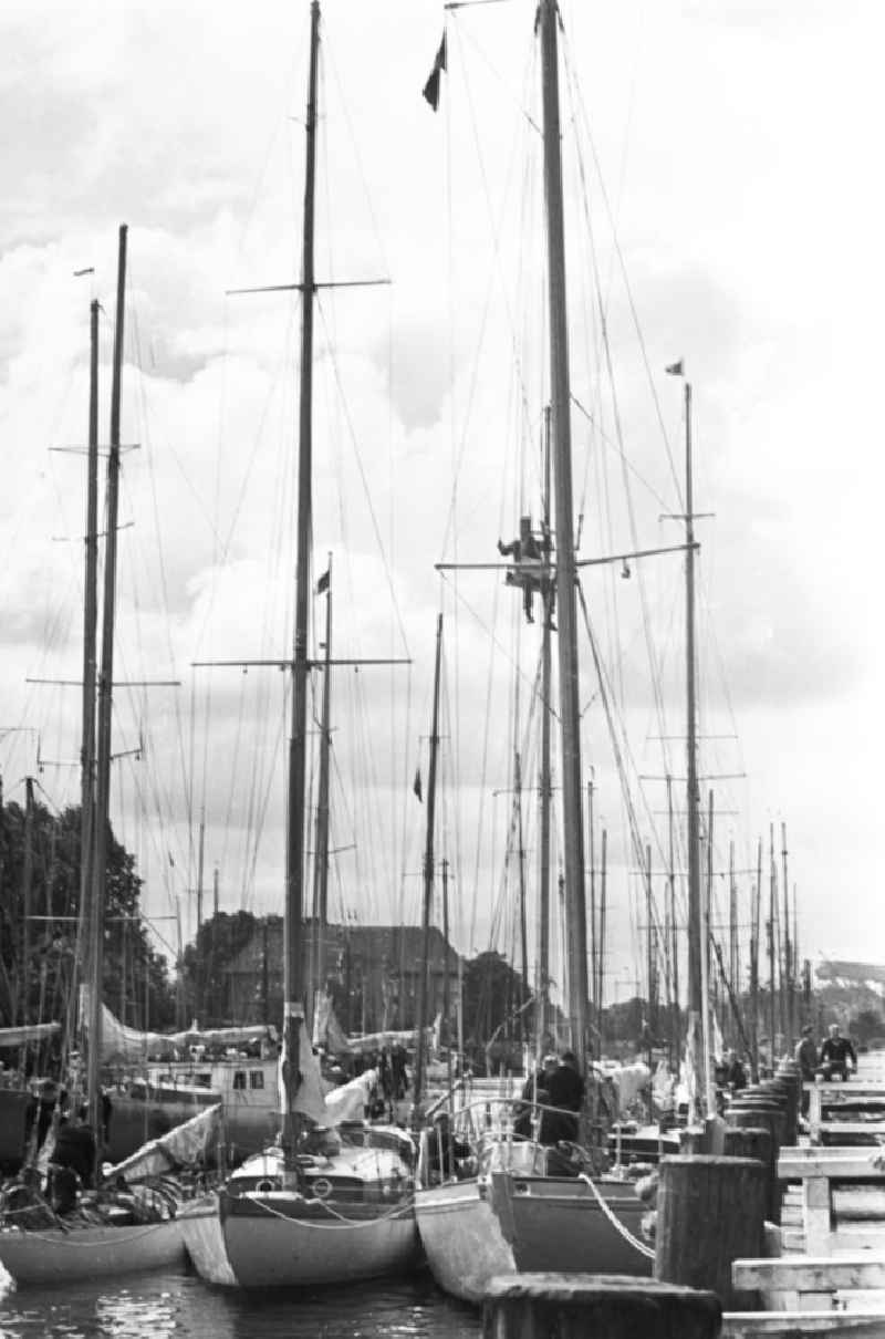 Während der Ostseewoche - Segelschiffe / Sebelboote im Yachthafen / Hafen / Marina in Rostock Warnemünde. In Rostock und anderen Orten an der Ostseeküste fand jedes Jahr die Ostseewoche statt, die zahlreiche politische, kulturelle und sportliche Veranstaltungen umfasste. Ziel der Ostseewoche war es, die Beziehungen der DDR zu benachbarten nordeuropäischen Ländern zu pflegen und die staatliche Anerkennung der DDR voran zu bringen. Bestmögliche Qualität nach Vorlage!