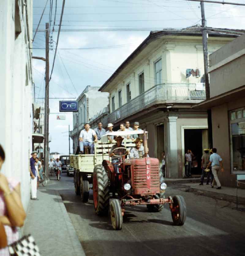 Straßenszene in Santa Clara in Kuba - ein Traktor fährt mit Arbeitern zum Ernteeinsatz. Street scene in Santa Clara - Cuba. A tractor drives on the road.