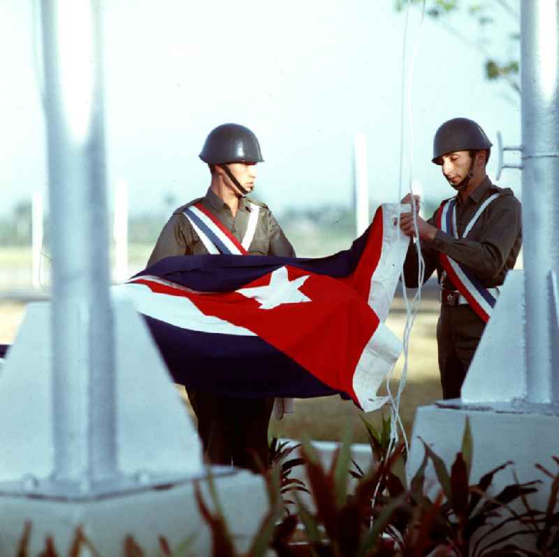 Zum Empfang des Staats- und Parteivorsitzenden der DDR, Erich Honecker, auf dem Flughafen Santiago de Cuba wird von zwei Soldaten die kubanische Flagge gehißt. Honecker stattete vom 2