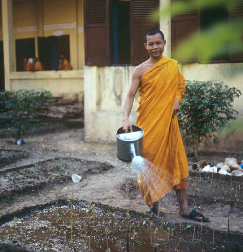 Mönche in den charakteristischen safrangelben Gewändern bei ihrer täglichen Arbeit in einem buddhistischen Tempel in Vientiane, der Hauptstadt der Demokratischen Volksrepublik Laos. Bis zur Ausrufung der Volksrepublik Laos am 2. Dezember 1975 bestimmte der Theravada-Buddhismus die kulturelle Entwicklung im Land. Nachdem die anfängliche Unterdrückung der traditionellen buddhistischen Bräuche durch die neuen kommunistischen Machthaber mißlang, fand Laos in den folgenden Jahrzehnten einen eigenen Weg der Koexistenz von Buddhismus und Sozialismus.