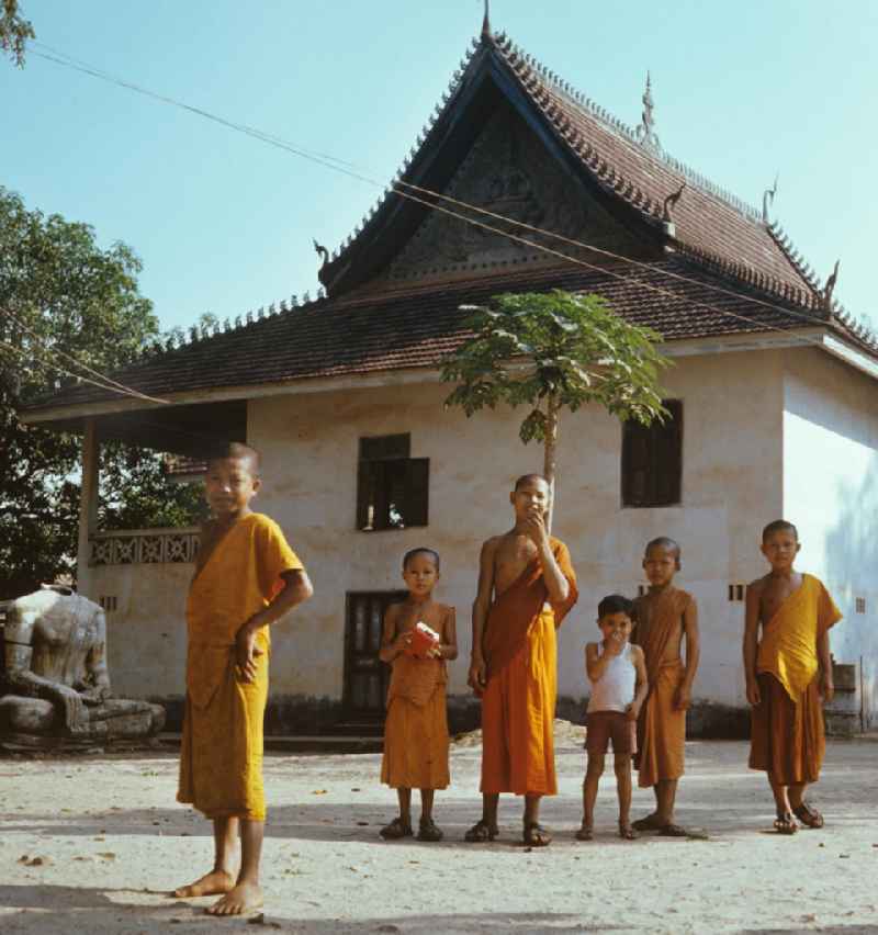 Kindermönche / Mönche in den charakteristischen safrangelben Gewändern in einem buddhistischen Tempel in Vientiane, der Hauptstadt der Demokratischen Volksrepublik Laos. Bis zur Ausrufung der Volksrepublik Laos am 2. Dezember 1975 bestimmte der Theravada-Buddhismus die kulturelle Entwicklung im Land. Nachdem die anfängliche Unterdrückung der traditionellen buddhistischen Bräuche durch die neuen kommunistischen Machthaber mißlang, fand Laos in den folgenden Jahrzehnten einen eigenen Weg der Koexistenz von Buddhismus und Sozialismus.