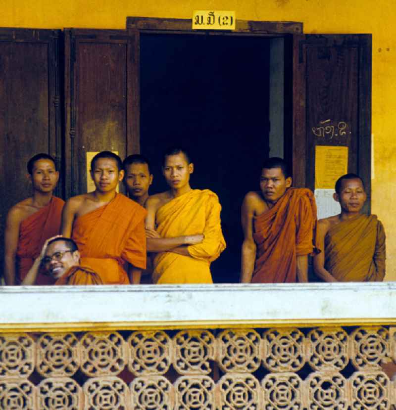 Mönche in den charakteristischen safrangelben Gewändern in einem buddhistischen Tempel in Vientiane, der Hauptstadt der Demokratischen Volksrepublik Laos. Bis zur Ausrufung der Volksrepublik Laos am 2. Dezember 1975 bestimmte der Theravada-Buddhismus die kulturelle Entwicklung im Land. Nachdem die anfängliche Unterdrückung der traditionellen buddhistischen Bräuche durch die neuen kommunistischen Machthaber mißlang, fand Laos in den folgenden Jahrzehnten einen eigenen Weg der Koexistenz von Buddhismus und Sozialismus.