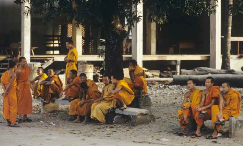 Mönche in den charakteristischen safrangelben Gewändern in einem buddhistischen Tempel in Vientiane, der Hauptstadt der Demokratischen Volksrepublik Laos. Bis zur Ausrufung der Volksrepublik Laos am 2. Dezember 1975 bestimmte der Theravada-Buddhismus die kulturelle Entwicklung im Land. Nachdem die anfängliche Unterdrückung der traditionellen buddhistischen Bräuche durch die neuen kommunistischen Machthaber mißlang, fand Laos in den folgenden Jahrzehnten einen eigenen Weg der Koexistenz von Buddhismus und Sozialismus.