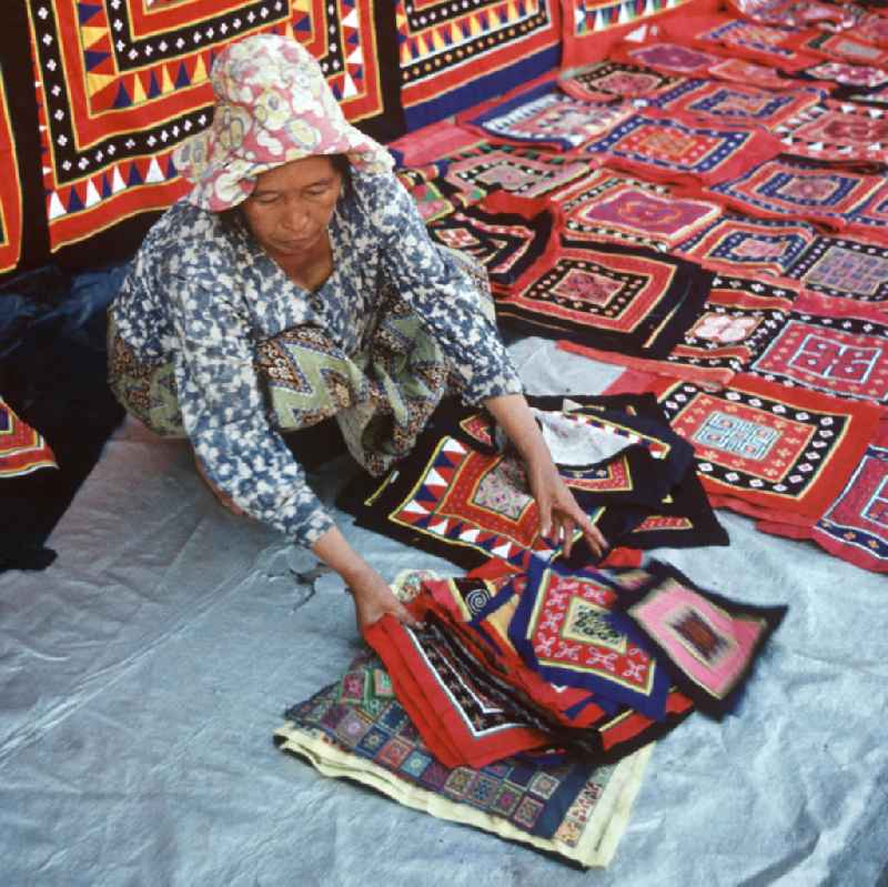 Eine Frau aus dem Volksstamm der Meo, auch Hmong genannt, verkauft selbstgenähte Decken in Vientiane, der Hauptstadt der Demokratischen Volksrepublik Laos. Die Hmong gehörten zu einer infolge des Vietnam-Krieges verfolgten und zurückgezogen lebenden Minderheit in Laos.