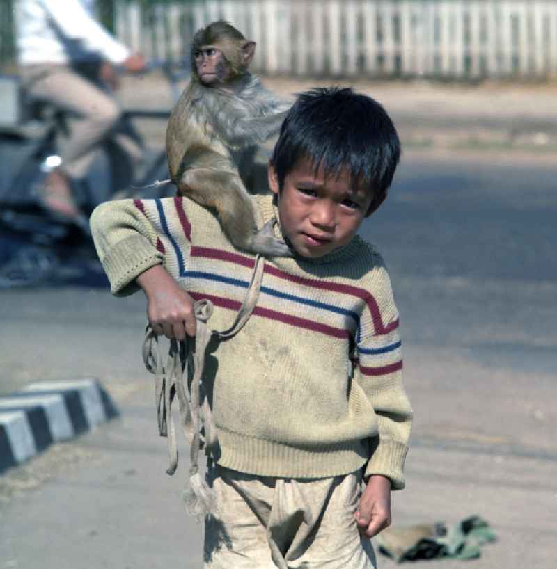 Ein Junge mit einem Affen auf seiner Schulter steht auf einer Straße in Vientiane, der Hauptstadt der Demokratischen Volksrepublik Laos.