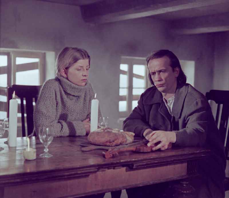 Scene from the film and television production 'Rublak - The Legend of the Surveyed Land' in the Haide district of Weisskeissel, Saxony in the area of the former GDR, German Democratic Republic. The actor Christian Grashof and the actress Johanna Schall sit next to each other at a table in a farmhouse parlor