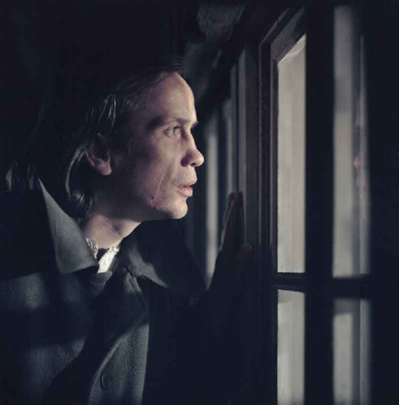 Scene from the film and television production 'Rublak - The Legend of the Surveyed Land' in the Haide district of Weisskeissel, Saxony in the area of the former GDR, German Democratic Republic. The actor Christian Grashof stands at the house at night and looks through the window into the farmhouse parlor