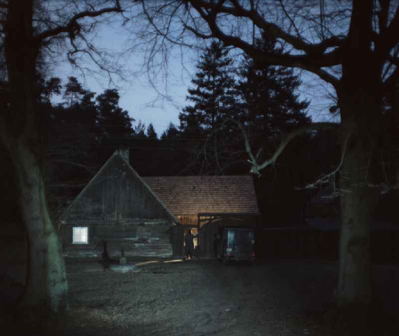 Scene from the film and television production 'Rublak - The Legend of the Surveyed Land' in the Haide district of Weisskeissel, Saxony in the area of the former GDR, German Democratic Republic. The actor Christian Grashof stands in front of it like a shadow and looks towards the entrance of a farmhouse