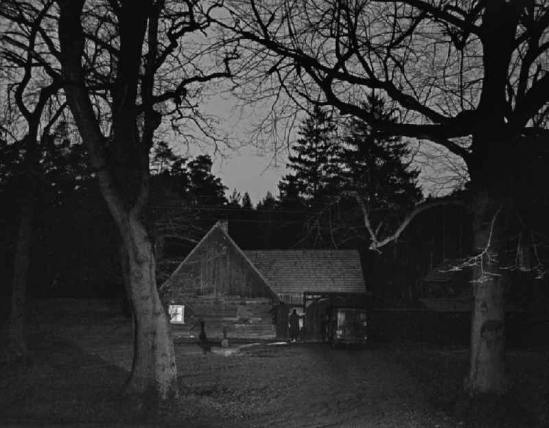 Scene from the film and television production 'Rublak - The Legend of the Surveyed Land' in the Haide district of Weisskeissel, Saxony in the area of the former GDR, German Democratic Republic. The actor Christian Grashof stands in front of it like a shadow and looks towards the entrance of a farmhouse